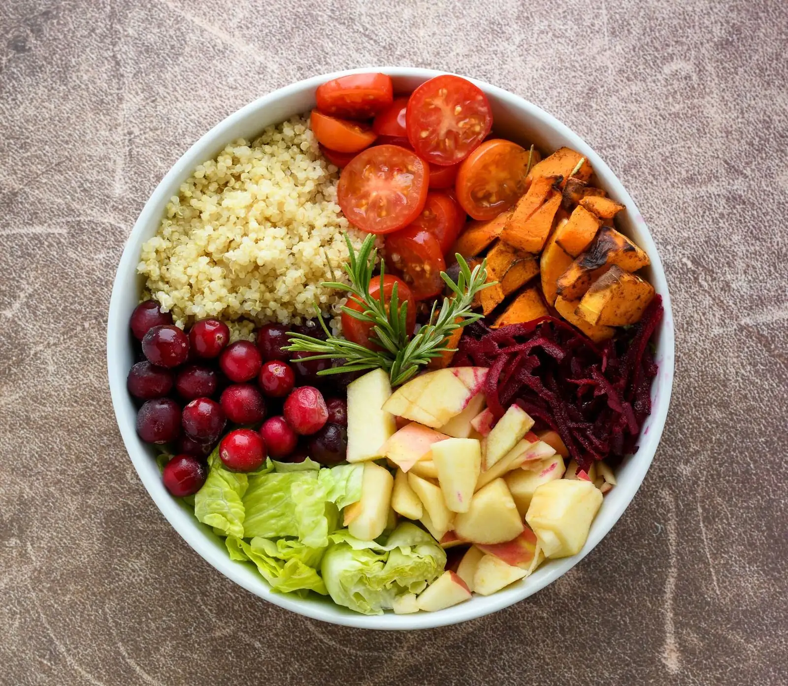 Quinoa bowl with tomatoes, roasted sweet potato, cranberries, apple and beetroot